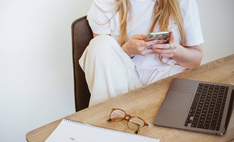 パソコンの前でスマホを操作している女性