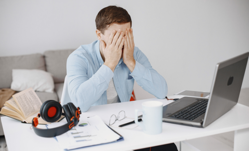 顔を隠して悩む男性