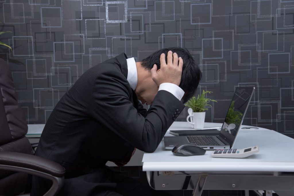 両手で頭を抱えているスーツ姿の男性