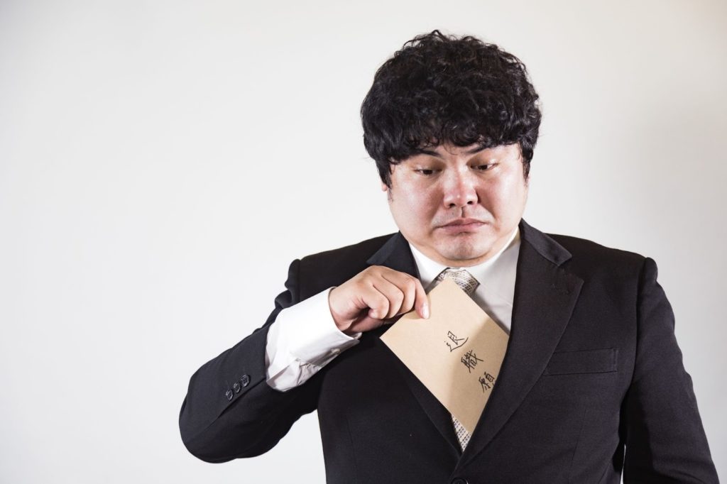 スーツの胸ポケットから、「退職願」の封筒を取り出そうとしている男性
