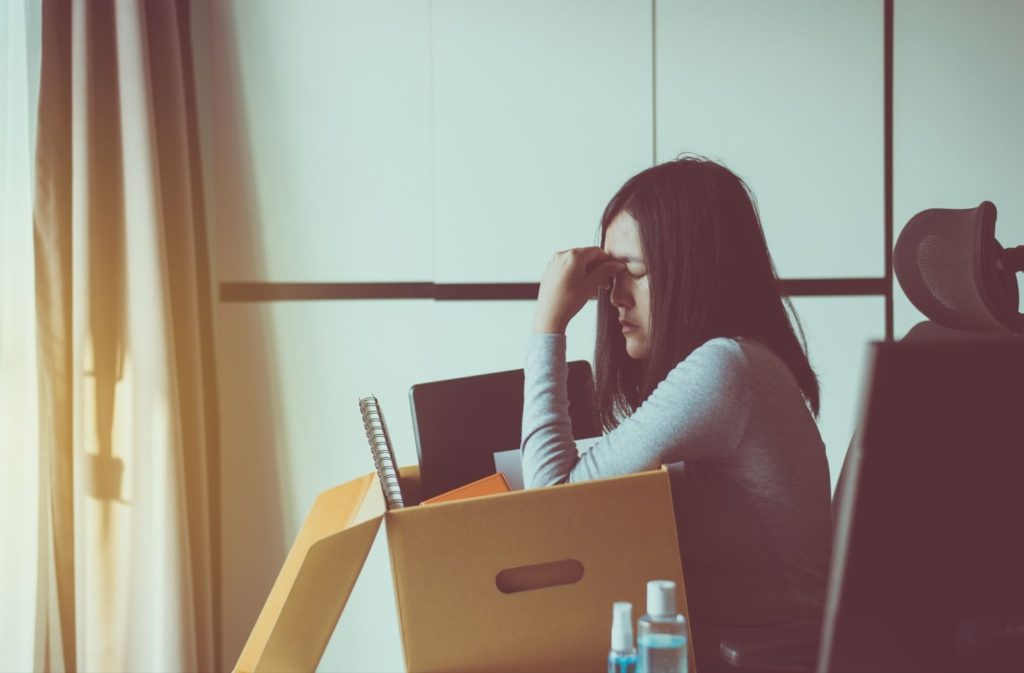 荷物を片手に、頭を抱える女性