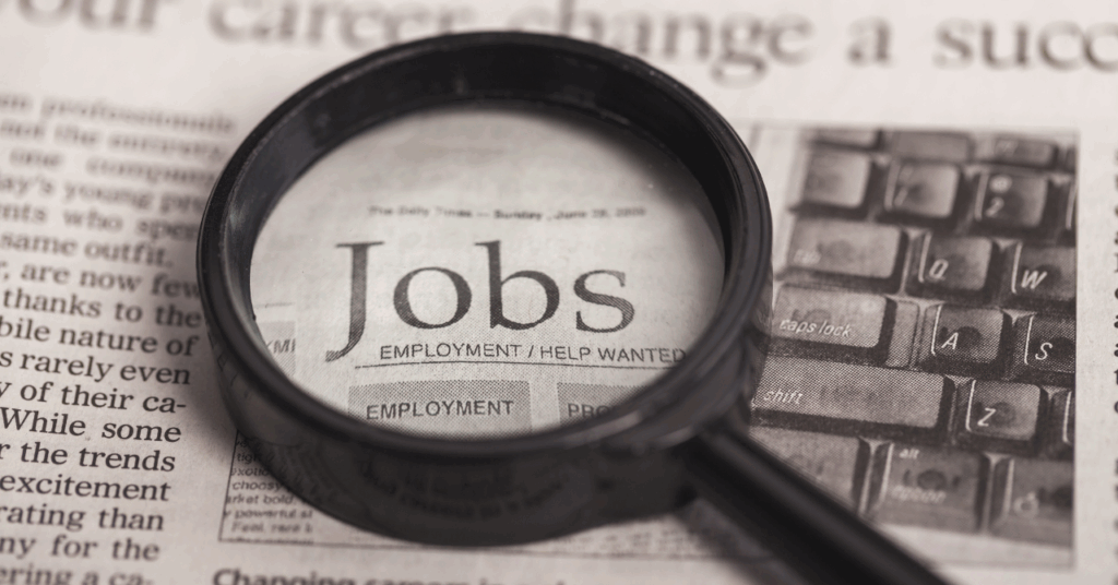 Jobsと新聞に書かれた文字を虫眼鏡で見ている