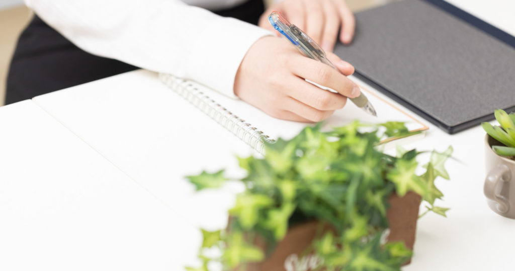 ノートに時を書く女性