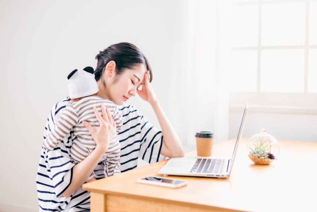赤ちゃんを抱っこしてパソコンの前にいる女性