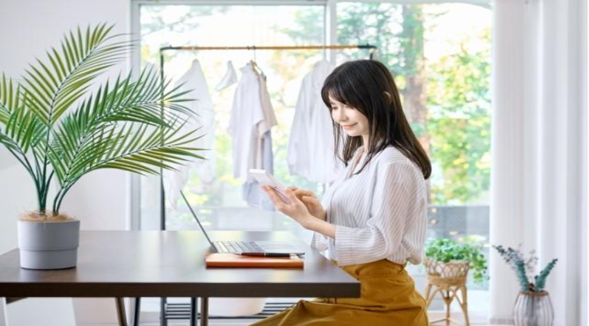 パソコンの前で電卓を使用する女性