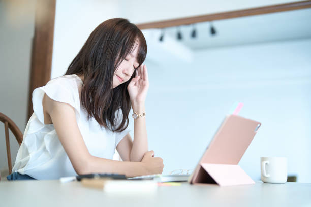 タブレットを開いた状態で頭を抱えている女性