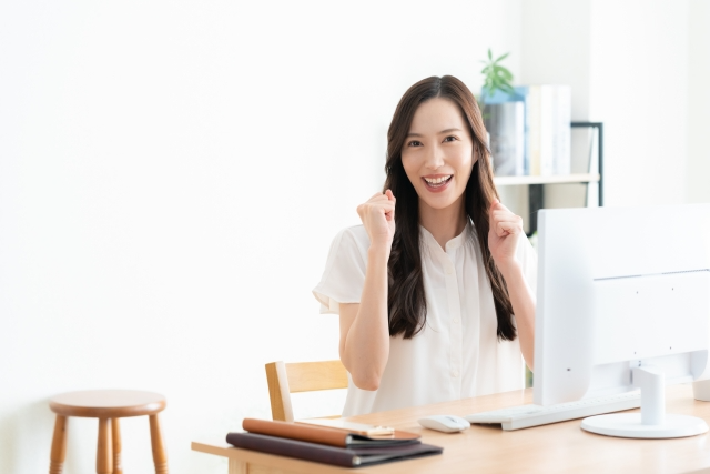 パソコンの前でガッツポーズをする女性