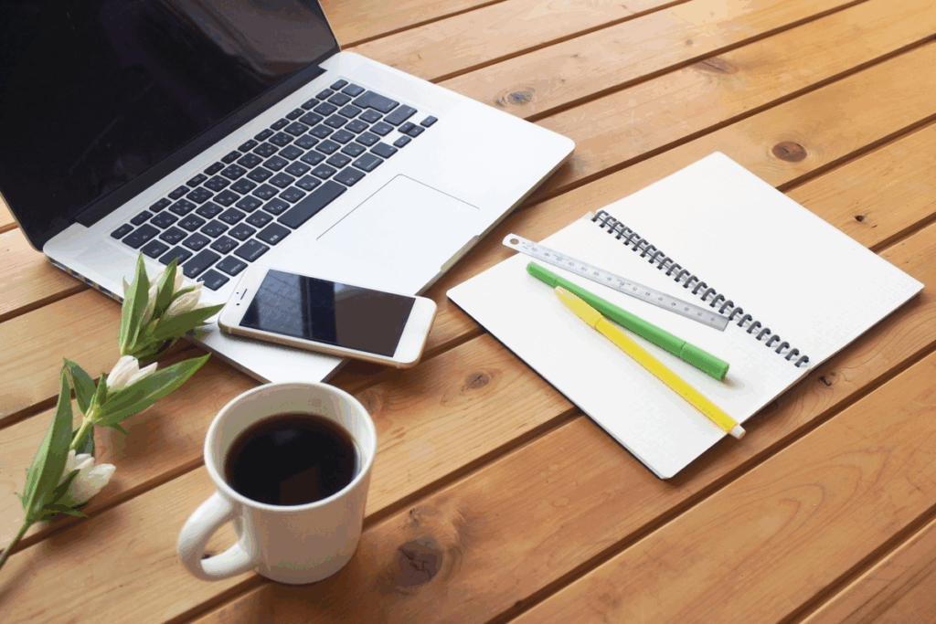 パソコンやスマホ、コーヒーが乱雑に置いてある