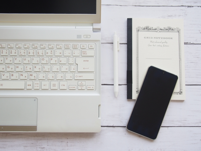 パソコンの横にスマホとノートがある