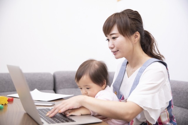 赤ちゃんを抱っこしながらパソコンを操作する女性