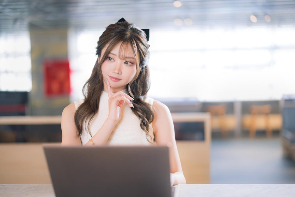 ノートパソコンを前に考える女性