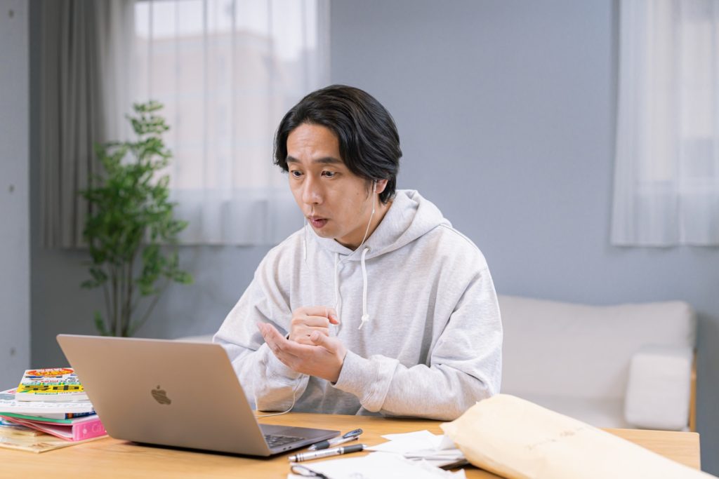 ノートパソコンを前に何かひらめいた様子の男性