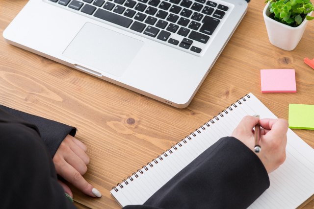 パソコンを開きつつ、ノートにメモを取る人