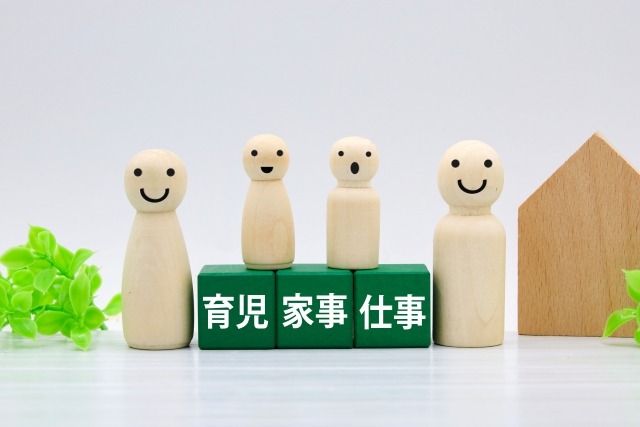 「育児・家事・仕事」と書かれた緑色のブロックの上に、笑顔の木製人形が並んでいる