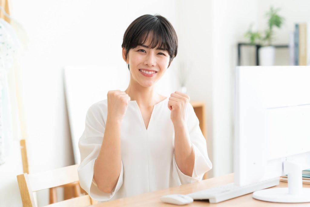 パソコンの前でガッツポーズする女性