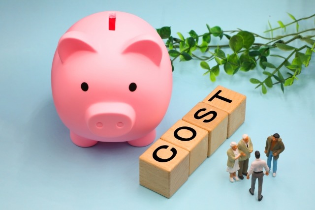 貯金箱とcostの文字、その横で話し合う人たち