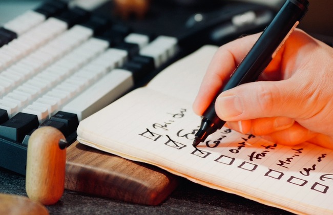 ノートにチェックを書いている手の画像