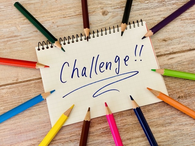 チャレンジと書かれたノートの周りに色鉛筆がある