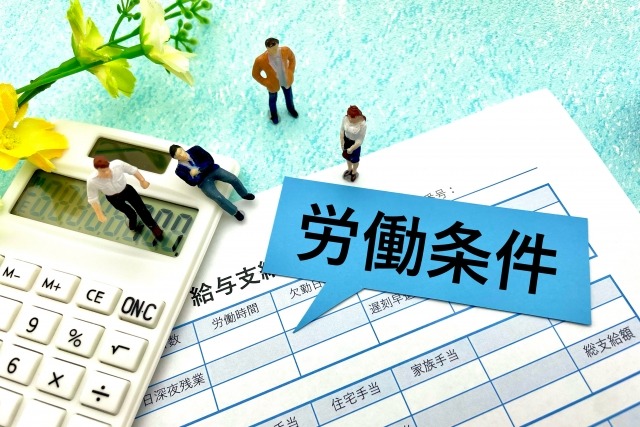 給与明細と電卓の上に労働条件と書かれた吹き出しがある