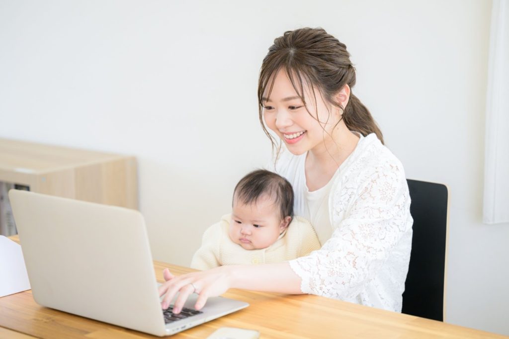 こどもを抱きながらPCを触っている