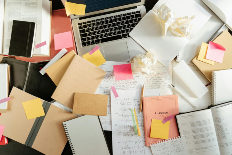 ノートパソコンがメモやノート類で埋まっている