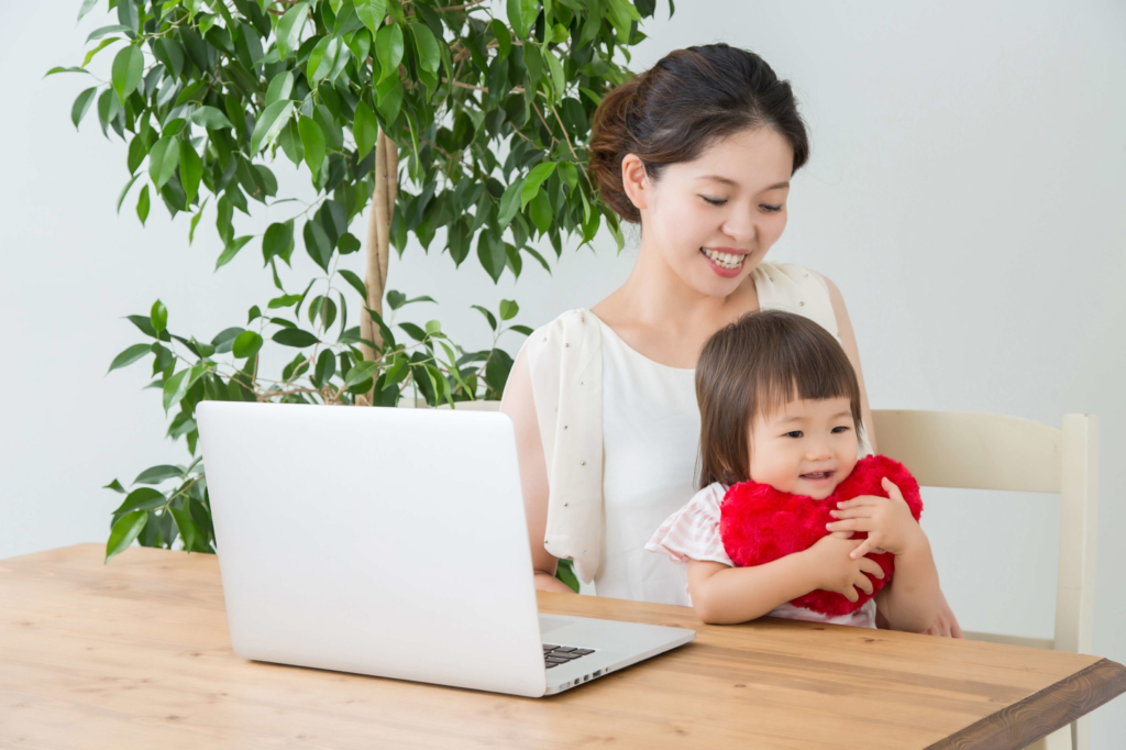 パソコンを開いた状態で赤ちゃんを抱っこしている女性
