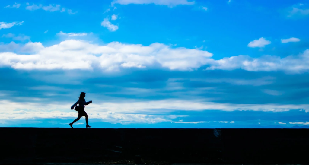 青空の下を歩く女性