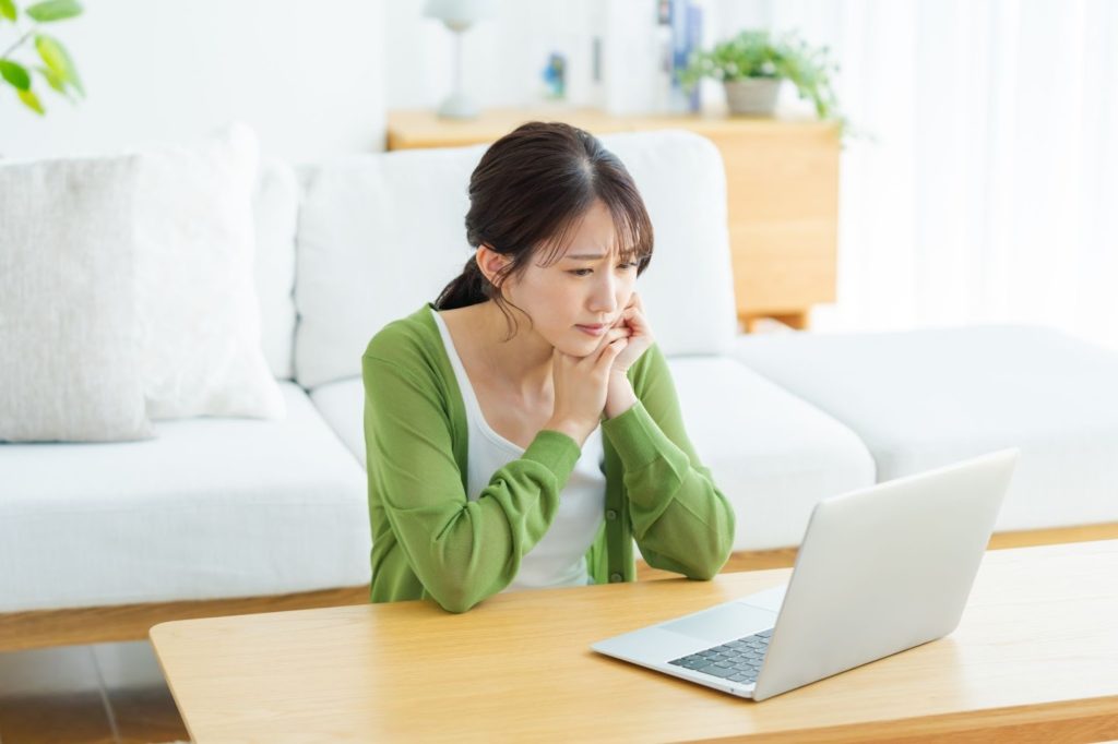 パソコンを見ながら不安そうな女性