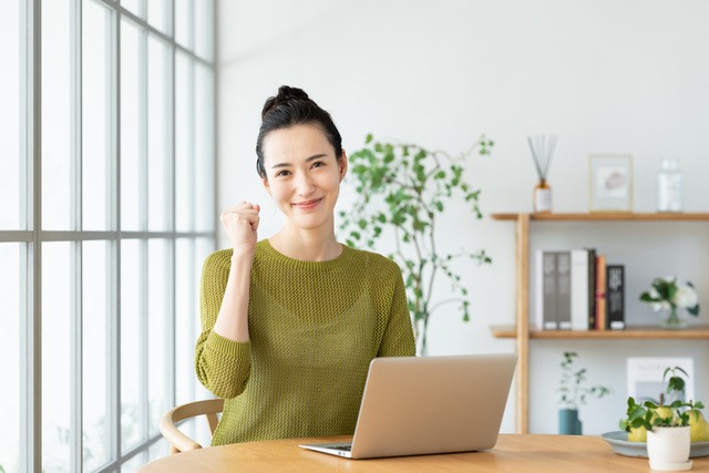 ノートパソコンを開き、ガッツポーズをする女性