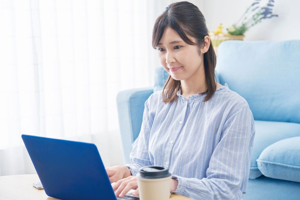自宅でノートパソコンを使用して作業する女性の写真