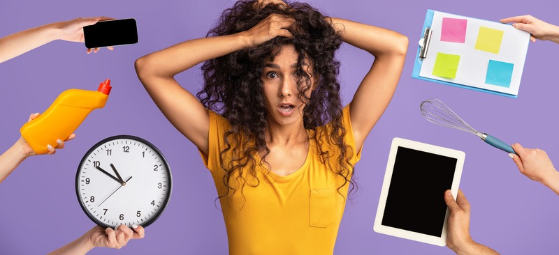 頭を抱える女性の周りにスマホや時計・調理グッズなどを差し出す人の手がある