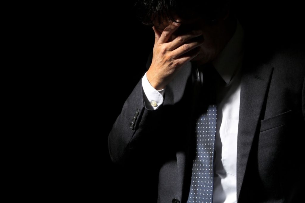 頭を抱えているスーツを着た男性