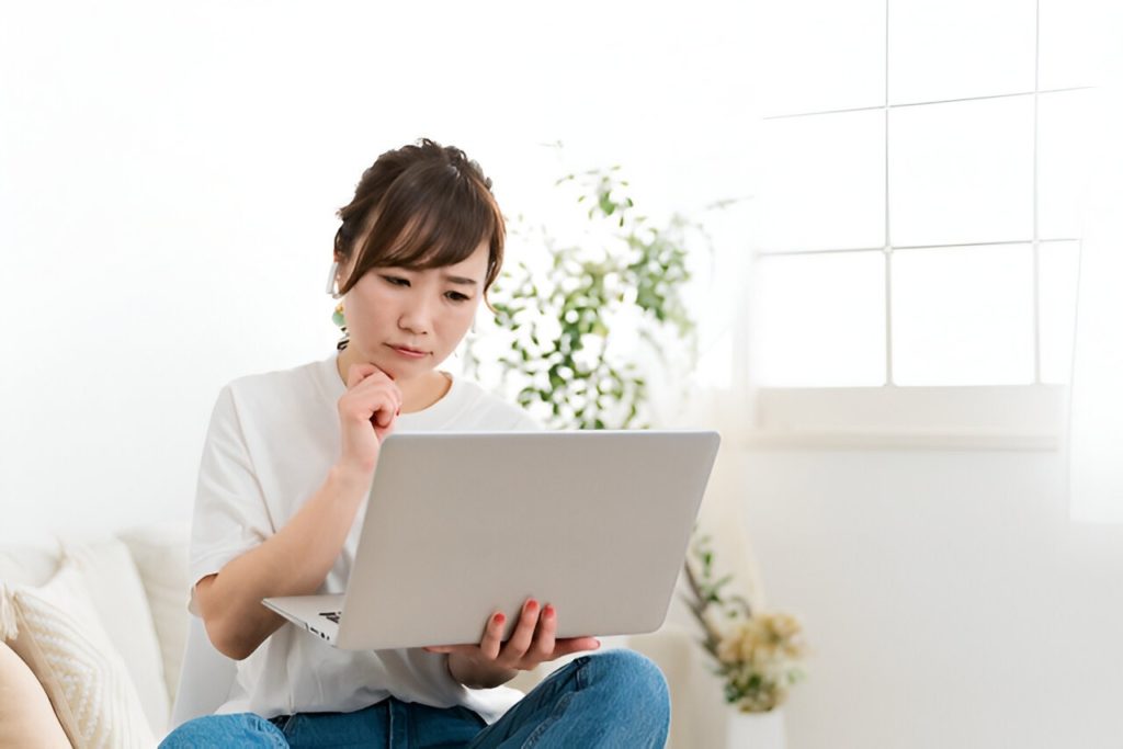ノートパソコンの画面を見ながら悩んでいる女性