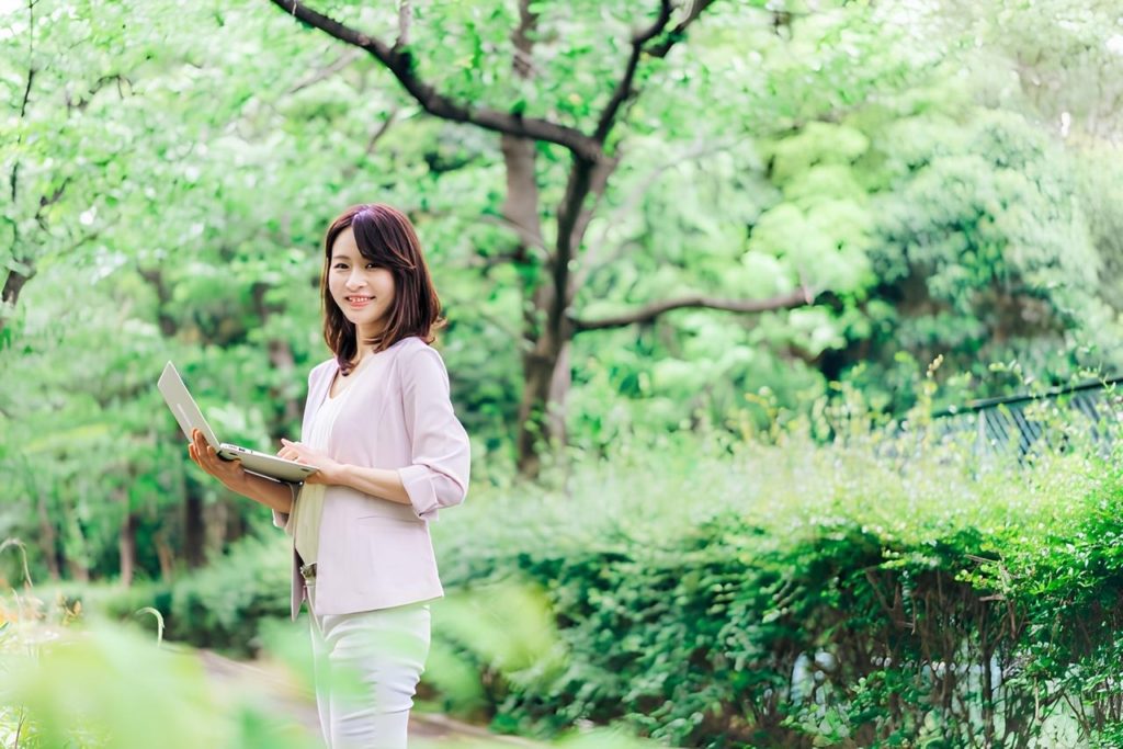 公園でノートパソコンを開いている女性