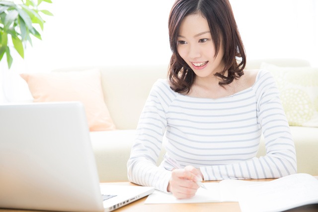 女性がパソコン画面を見ながら笑顔を浮かべている