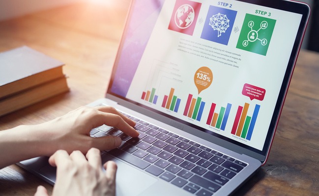 グラフの表示されたパソコンの上に手を置いている