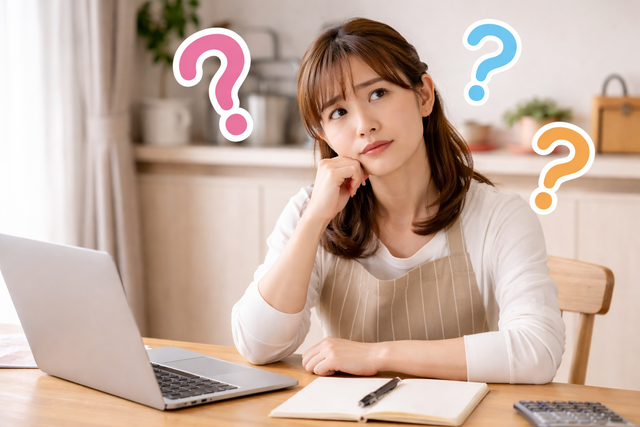 ノートパソコンの前で斜め上を見ながら悩んでいる表情の主婦（クエスチョンマーク付き）