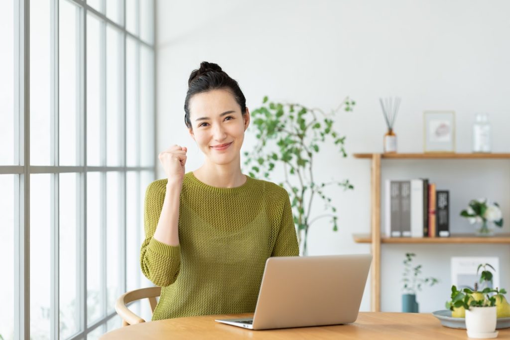 パソコンの前でガッツポーズで微笑んでいる女性