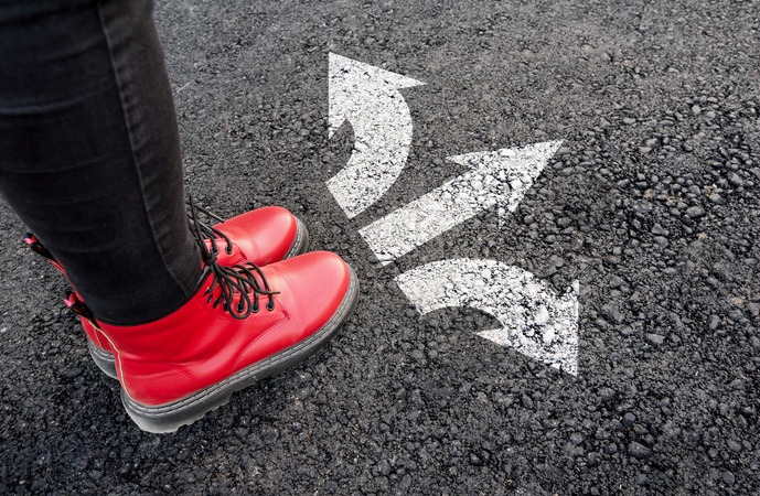 道路に書かれた3つの矢印の前で立ち止まっている人