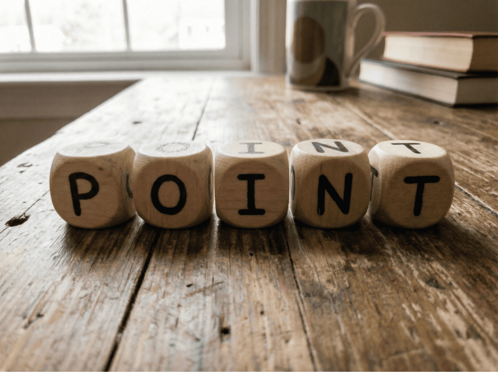 木製のサイコロが5つ机の上に並んでおり、それぞれに「P」「O」「I」「N」「T」と書かれている