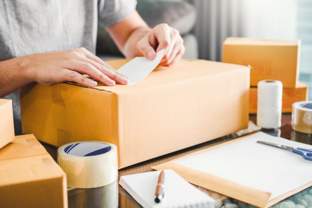 段ボールに宛名を張り、梱包作業を行う人の写真