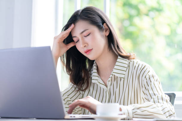 女性が頭を抱えてパソコンに向かっている。