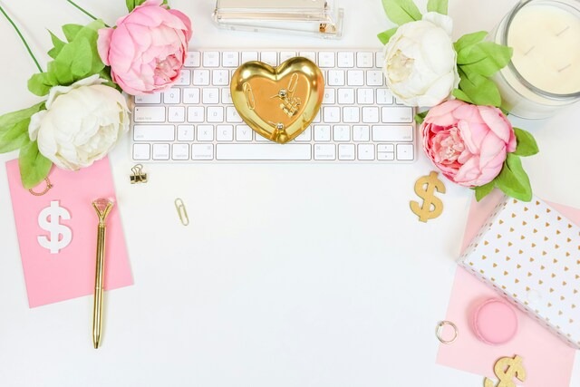 パソコンのキーボードの周りに、白とピンクの花や文房具が置かれている