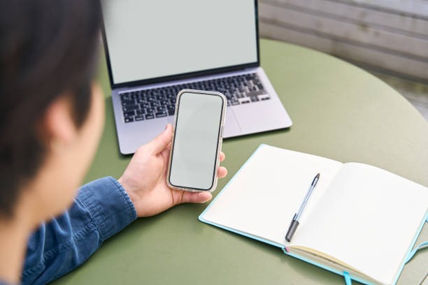 男性が手帳を開きながら、スマホを見ている。