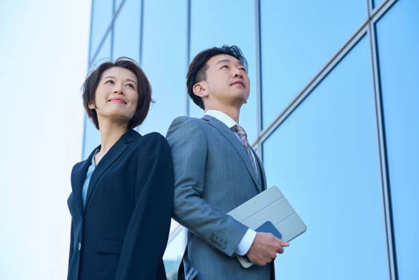 男女が背中合わせに、希望を持った表情で視線を少し先に同じ方向を見ている。