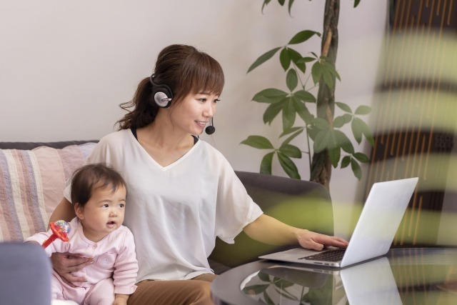 赤ちゃんを抱えながらパソコンを操作する女性