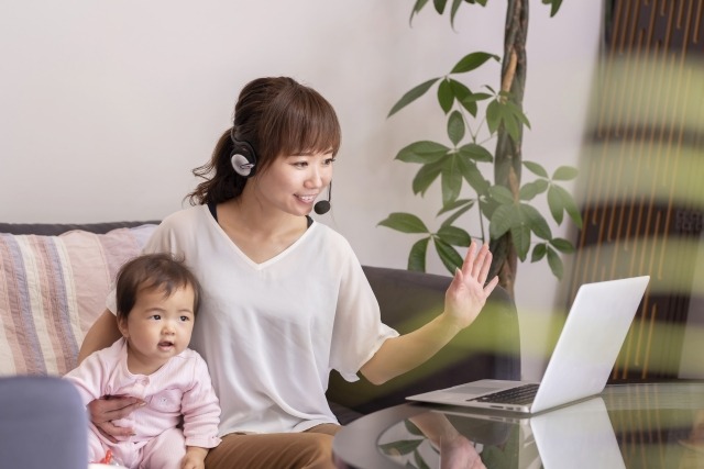 赤ちゃんを抱えながらPCに向かって会話する女性